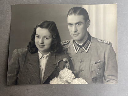 WW2 Tysk Stort "Studiofoto". Soldat i sommer kampuniform, med sabel, skydesnor, medaljer mv. Original.