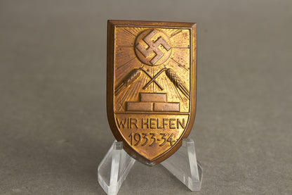 WW2 Tysk Tidlig 1933/34 "Wir Helfen" WHW/NSDAP Tinnie. Sjælden. Original.